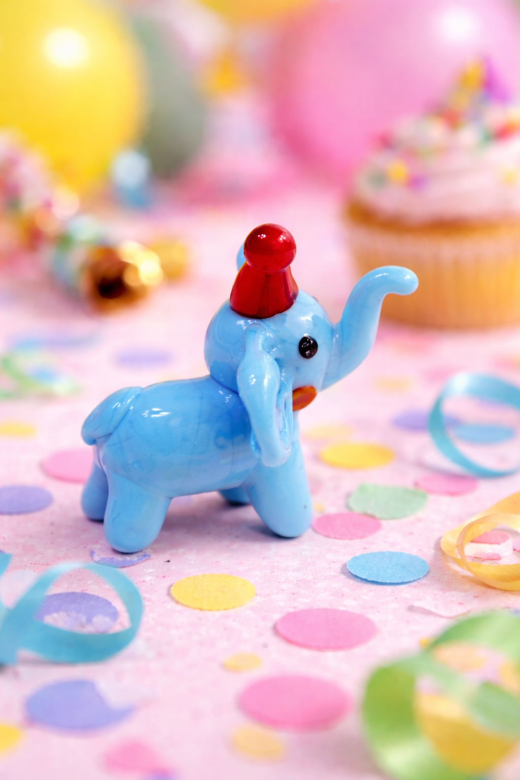 Colorful toy elephant with a red hat on a festive background with balloons and streamers.